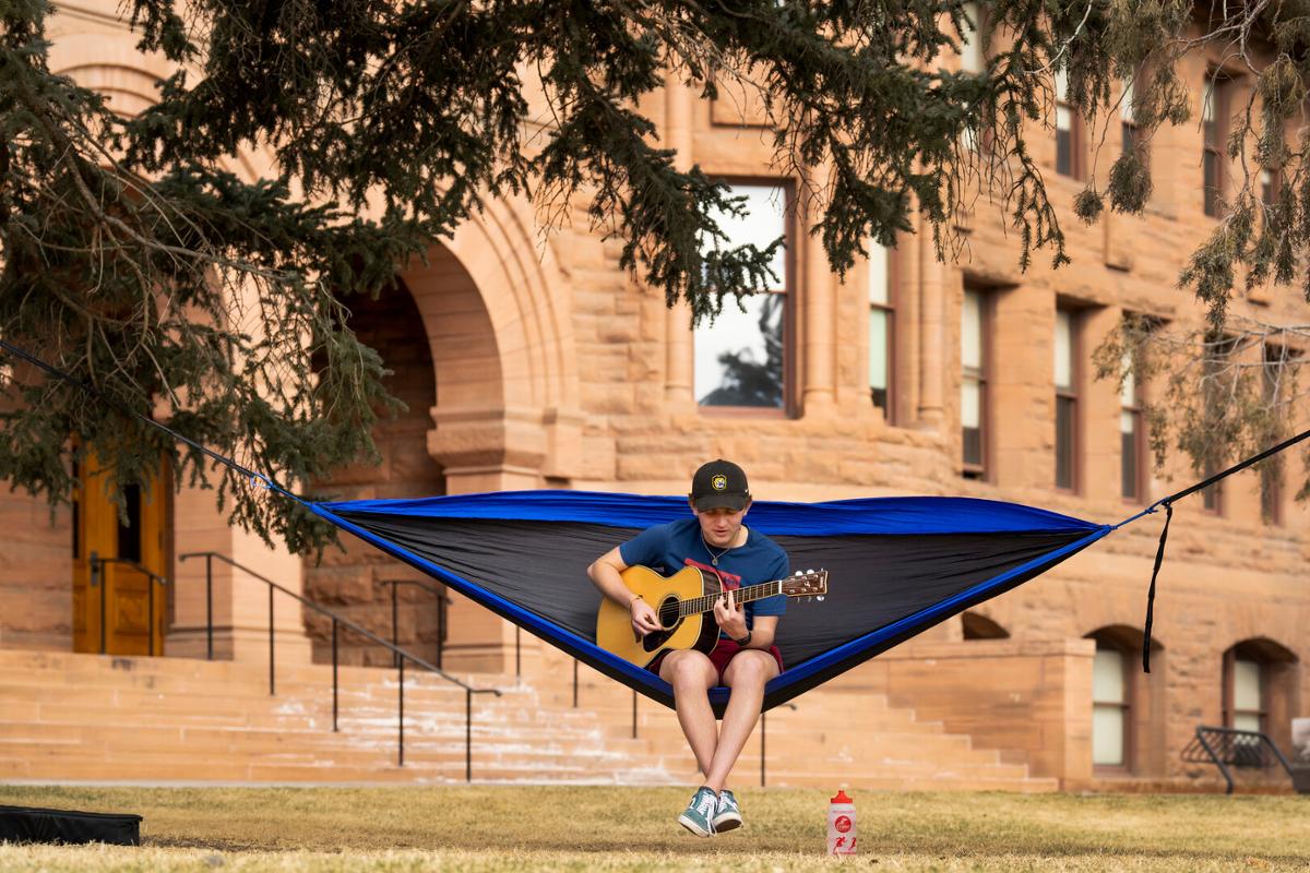 Max Saliman ’23 plays guitar near Palmer Hall during a warm winter day in Tava Quad on 3/15/23. Photo by Lonnie Timmons III / Colorado College.